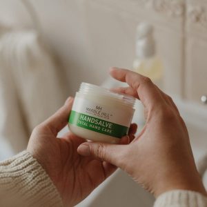 Hands holding jar of Marble Hill Handsalve Total Hand Care cream