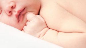 Sleeping baby with hand up to face showing soft, delicate skin