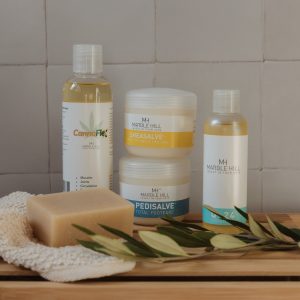 Display of Marble Hill Natiral Skincare Products (CannaFlex, SheaSalve, Pedisalve,Q24 Body Oil, Neem OIl soap) with tiled background